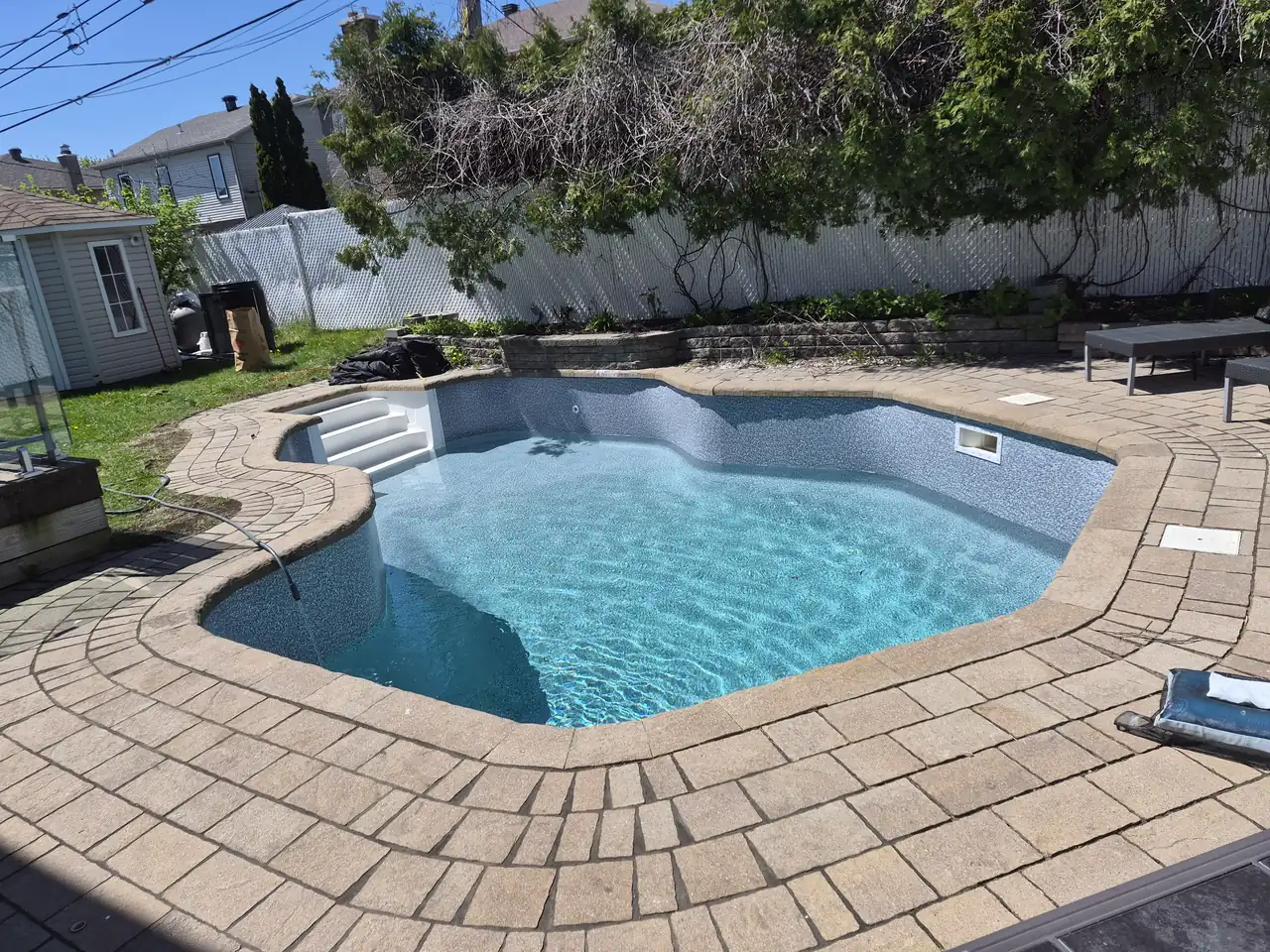 Piscine creusée à l’eau claire entourée d’une plage de pavés